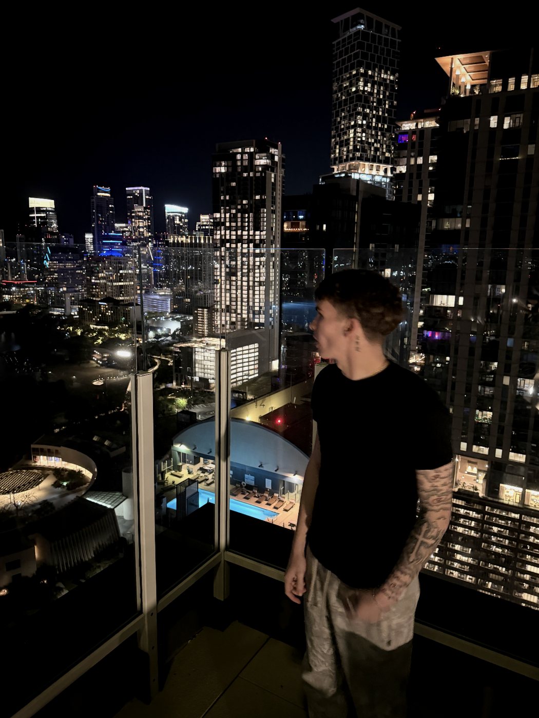 Travis on a high-rise balcony over the Austin skyline at night